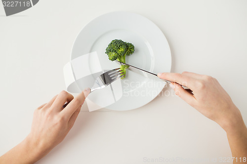 Image of close up of woman hands eating broccoli
