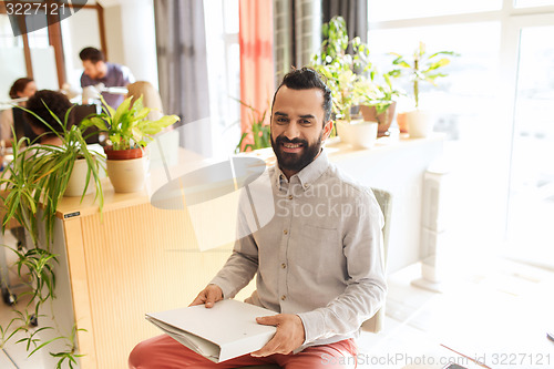Image of happy creative male office worker with folfer