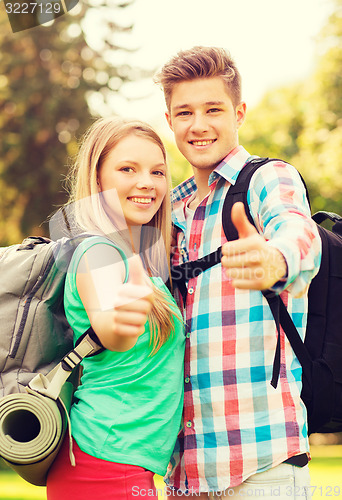 Image of smiling couple with backpacks showing thumbs up