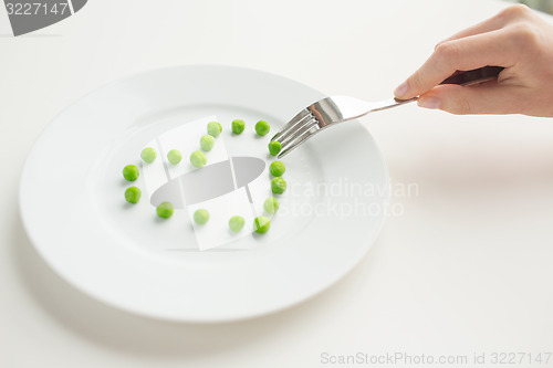 Image of close up of woman with fork eating peas