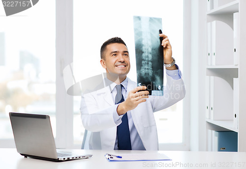 Image of smiling male doctor in white coat looking at x-ray