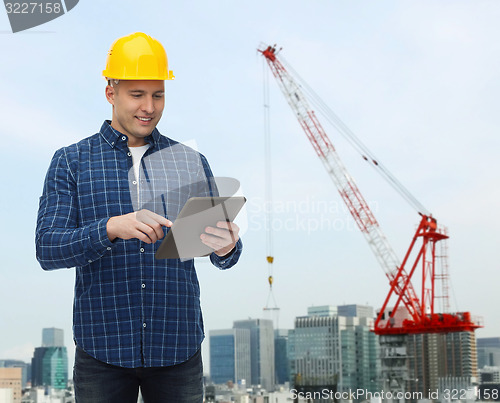 Image of smiling male builder in helmet with tablet pc