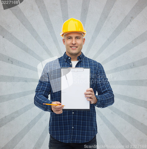 Image of smiling male builder in helmet with clipboard