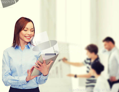 Image of smiling woman looking at tablet pc at office
