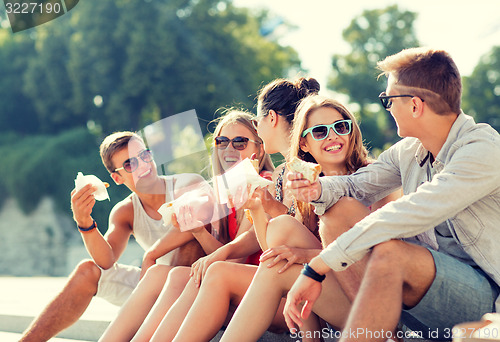 Image of group of smiling friends sitting on city square