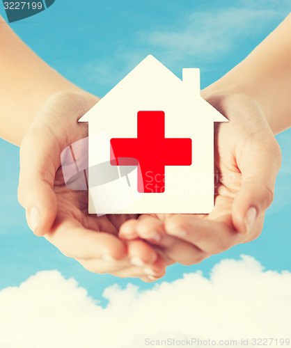 Image of hands holding paper house with red cross