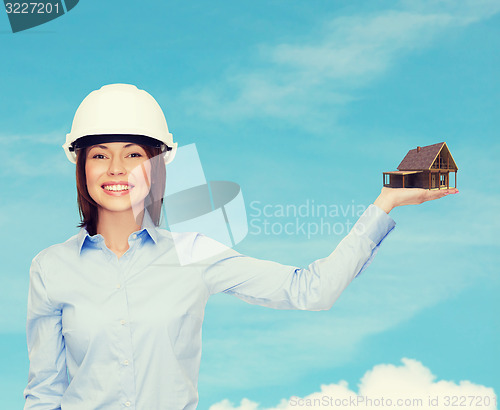 Image of businesswoman in helmet holding house on palm