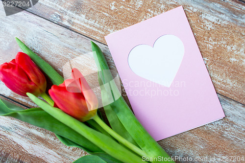 Image of close up of tulips and greeting card with heart