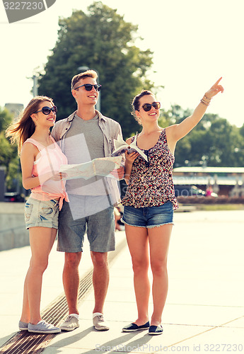 Image of smiling friends with map and city guide outdoors