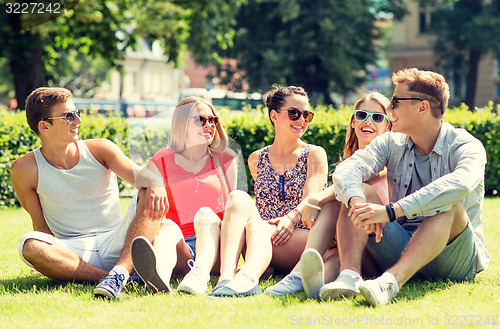 Image of group of smiling friends outdoors sitting on grass