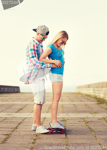 Image of smiling couple with skateboard outdoors