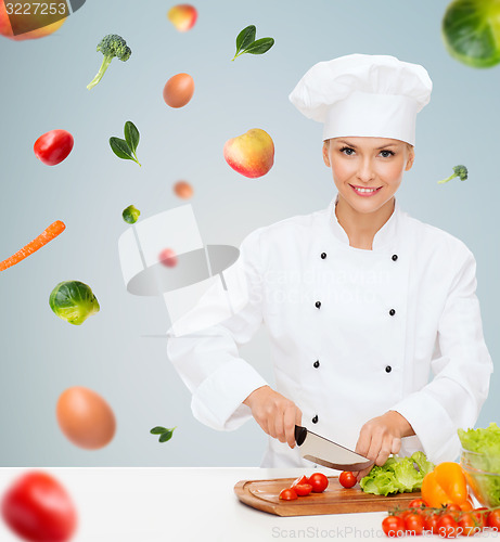 Image of smiling female chef chopping vegetables