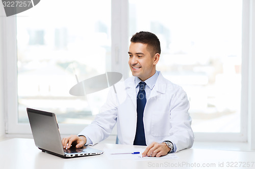 Image of smiling male doctor with laptop in medical office