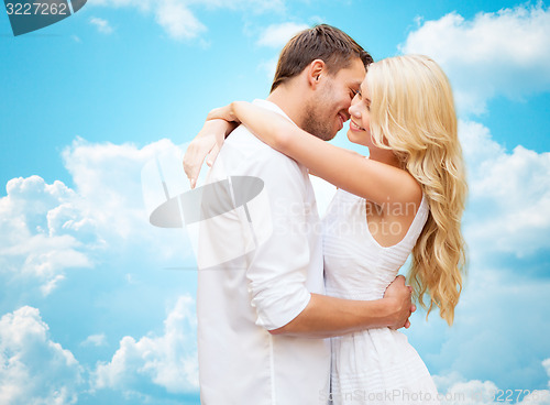 Image of happy couple hugging over blue sky