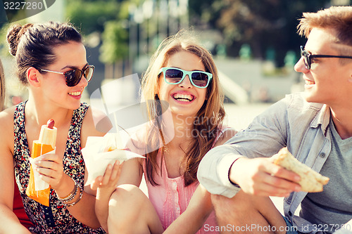 Image of group of smiling friends sitting on city square