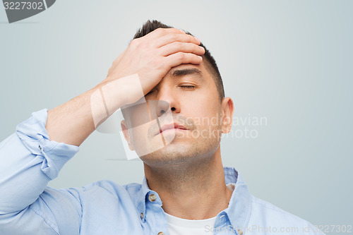 Image of unhappy man with closed eyes touching his forehead