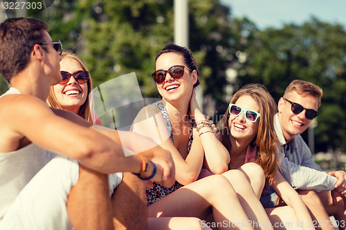 Image of group of smiling friends sitting on city street