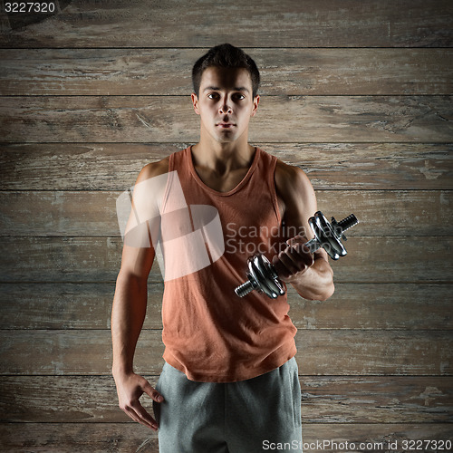 Image of young man with dumbbell flexing biceps