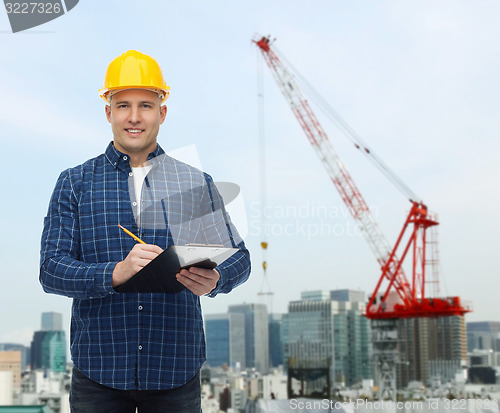 Image of smiling male builder in helmet with clipboard