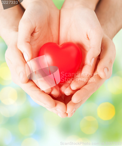 Image of close up of couple hands holding red heart