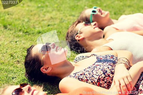 Image of group of smiling friends lying on grass outdoors