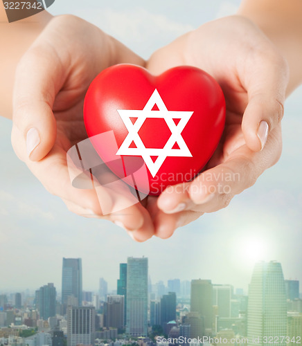 Image of close up of hands holding heart with jewish star