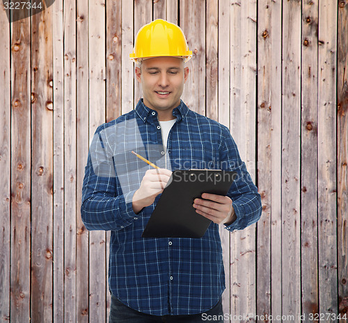 Image of smiling male builder in helmet with clipboard