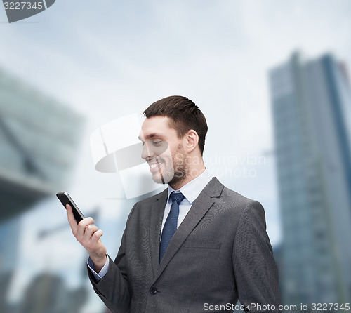 Image of young smiling businessman with smartphone