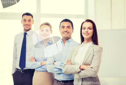 Image of smiling businesswoman in office with team on back