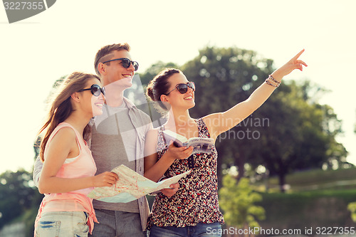 Image of smiling friends with map and city guide outdoors