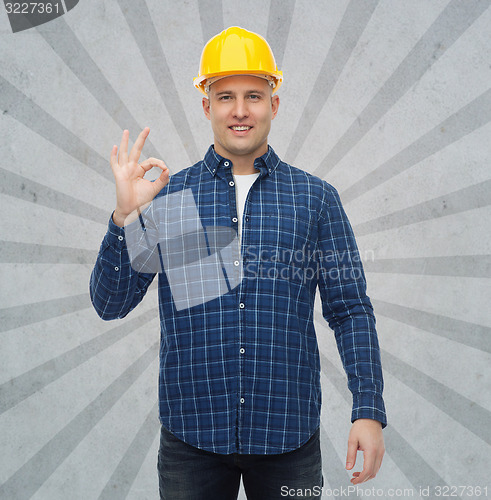 Image of smiling male builder in helmet showing ok sign