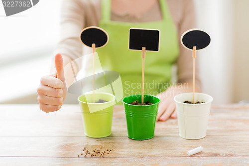 Image of close up of woman over pots with soil and signs