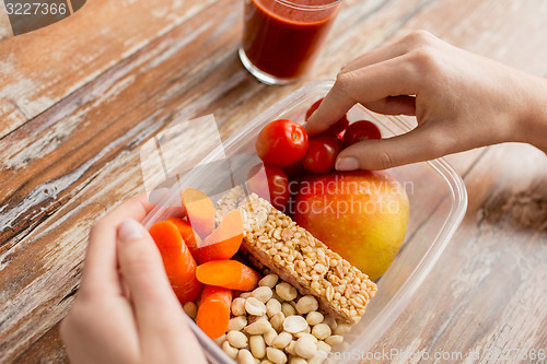 Image of close up of hands with vegetarian food in box