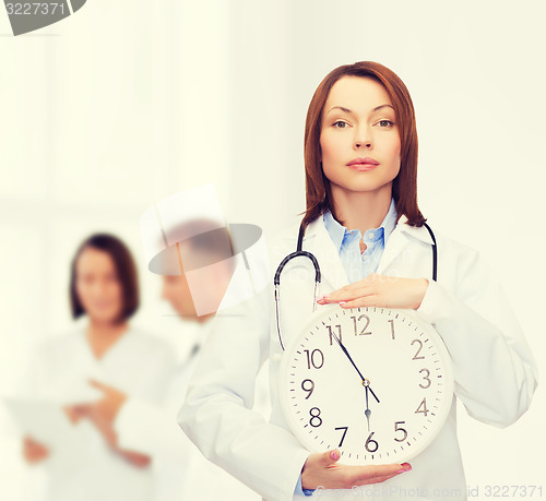 Image of calm female doctor with wall clock