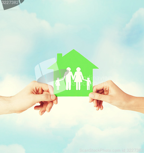 Image of hands holding green house with family