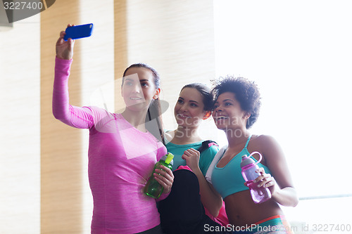 Image of happy women with smartphone taking selfie in gym