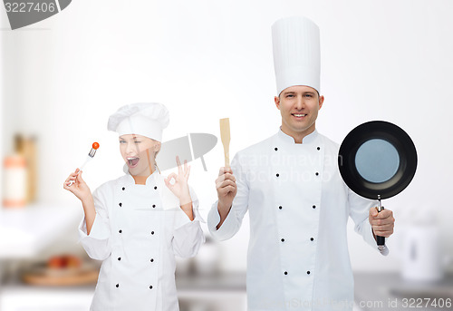 Image of happy male chef holding frying pan and spatula