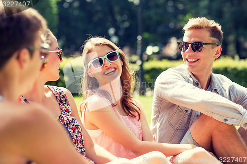 Image of group of smiling friends outdoors sitting in park