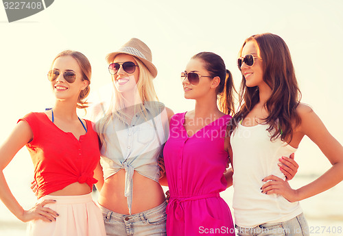 Image of group of smiling women in sunglasses on beach