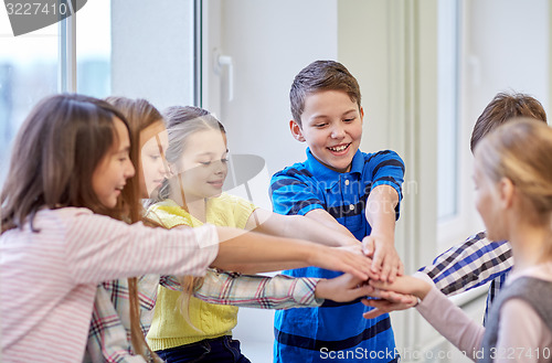 Image of group of smiling school kids putting hands on top