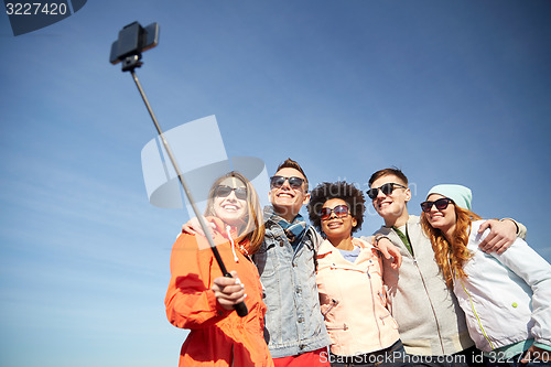 Image of smiling friends taking selfie with smartphone