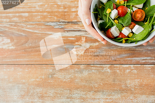 Image of close up of young woman hands with salad bowl