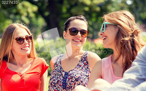 Image of group of smiling friends outdoors sitting in park