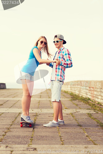 Image of smiling couple with skateboard outdoors