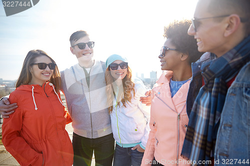Image of happy teenage friends in shades talking on street