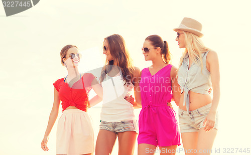 Image of group of smiling women in sunglasses on beach