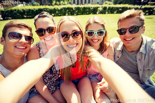 Image of group of smiling friends making selfie in park