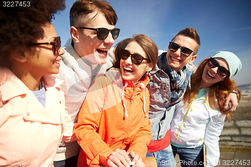 Image of smiling friends in sunglasses laughing on street