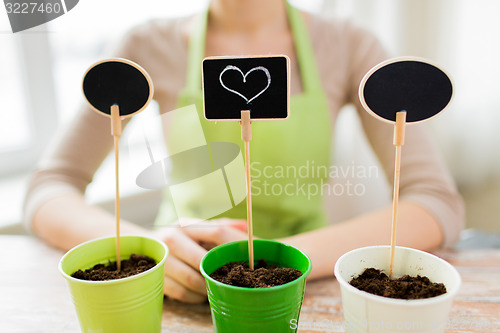 Image of close up of woman over pots with soil and signs