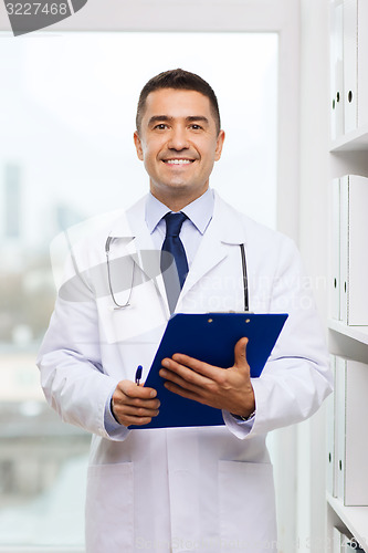 Image of happy doctor with clipboard in medical office